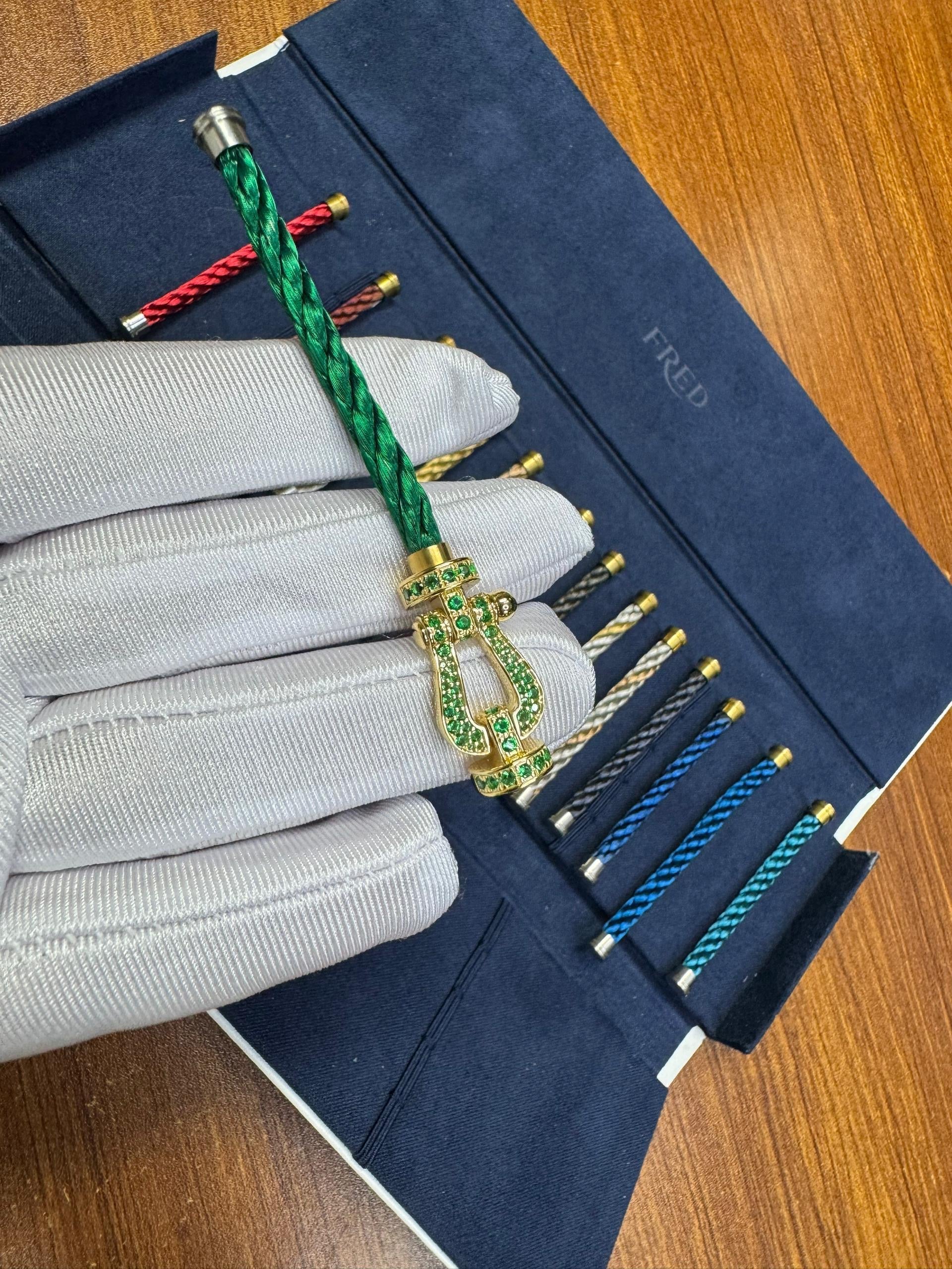 Luxuriöses Armband mit Seilband in Grün, goldfarbener Schließe, besetzt mit Zirkonia.