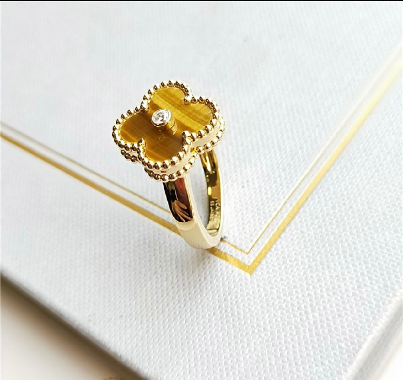 טבעת תלתן בגוון זהב – תלתן בגוון חום עם זירקון נוצץ במרכז