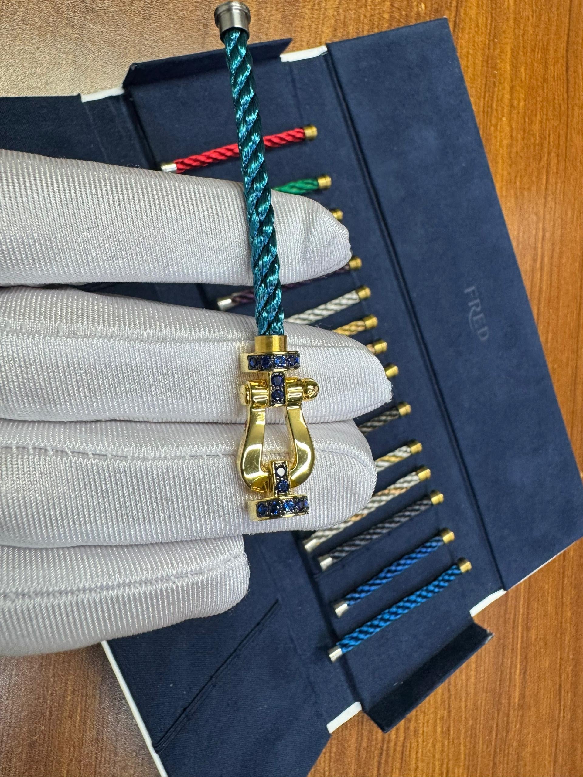 צמיד יוקרתי עם רצועת חבל בגוון ריביירה ואבזם בגוון זהב משובץ זירקונים עיצוב RG רולאן גארוס