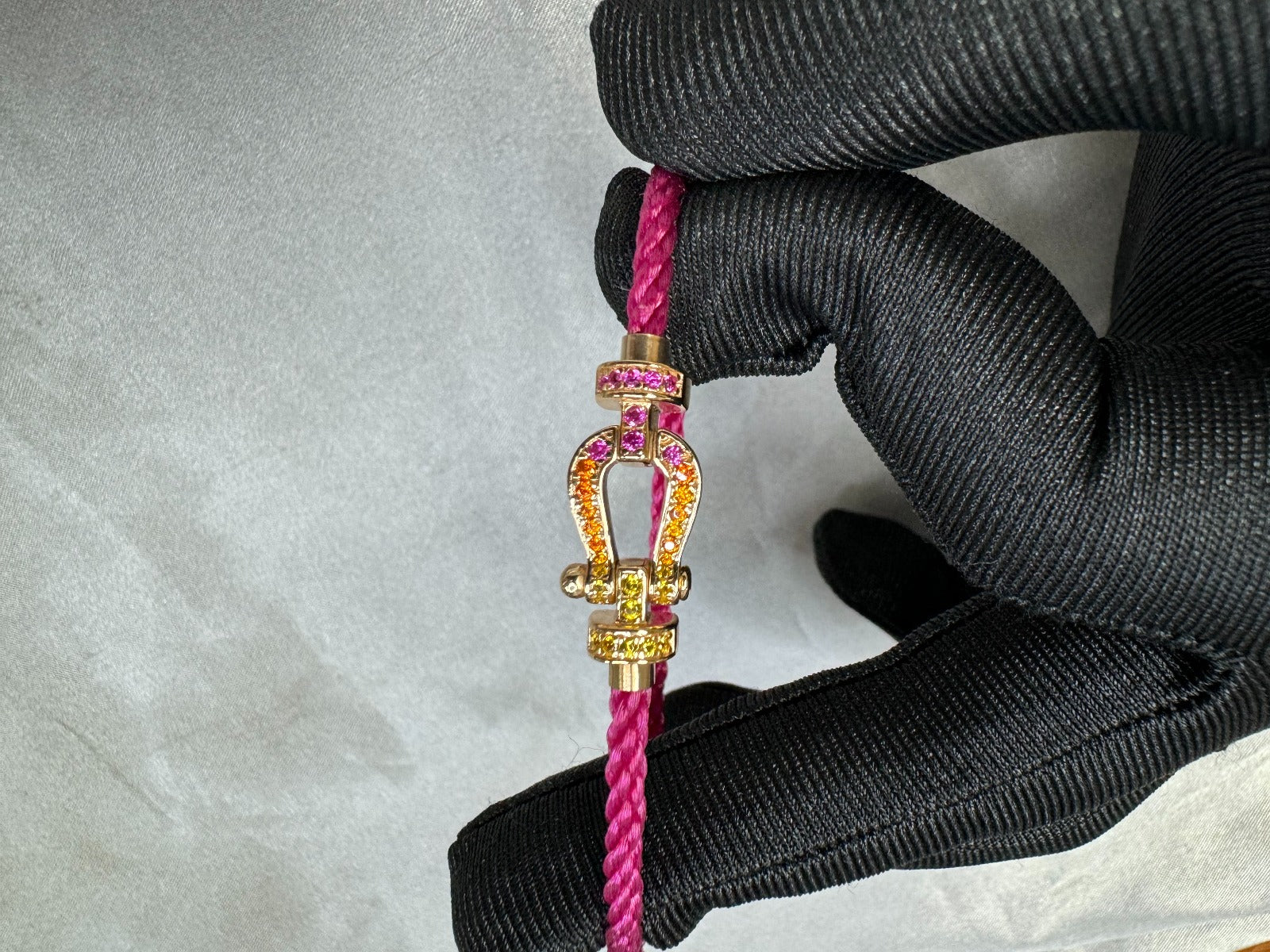 צמיד יוקרתי עם רצועת חבל ורודה דקה ואבזם בגוון זהב ורוד משובץ זירקונים צבעוניים