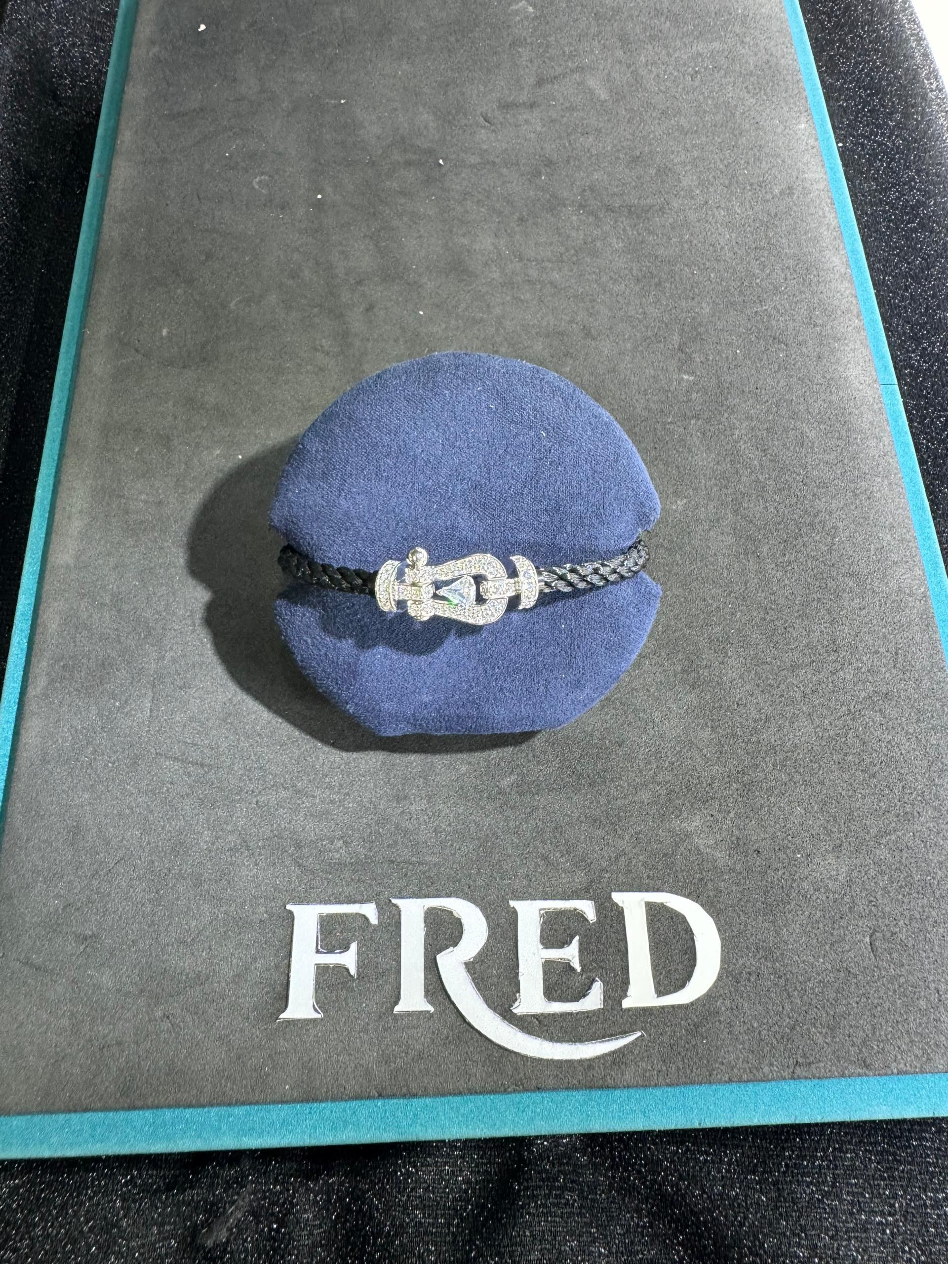 Bracelet luxueux avec une sangle en corde noire et une boucle argentée parsemée de zircons, avec une pierre centrale de 0,5 carat