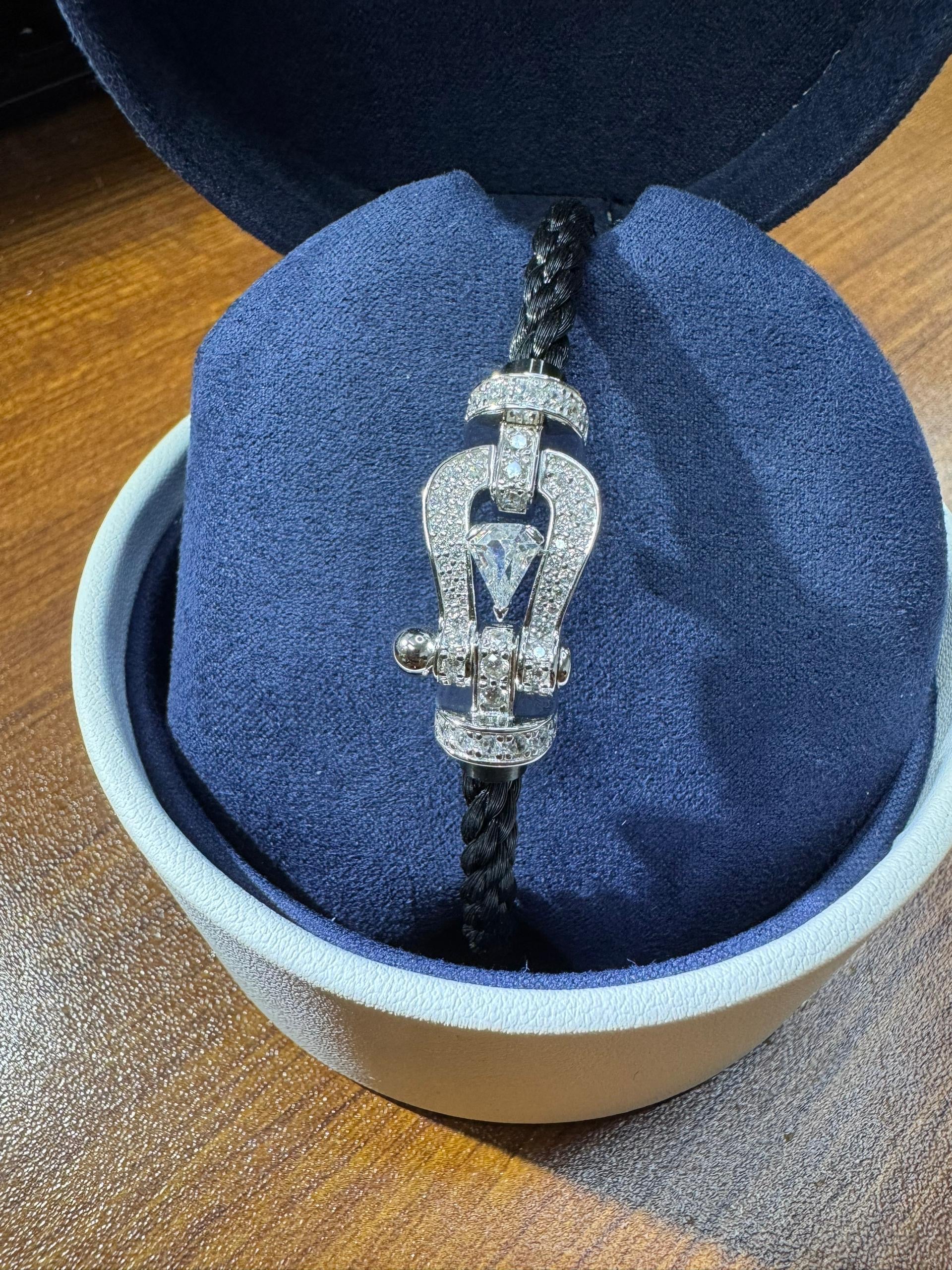 Bracelet luxueux avec une sangle en corde noire et une boucle argentée parsemée de zircons, avec une pierre centrale de 0,5 carat
