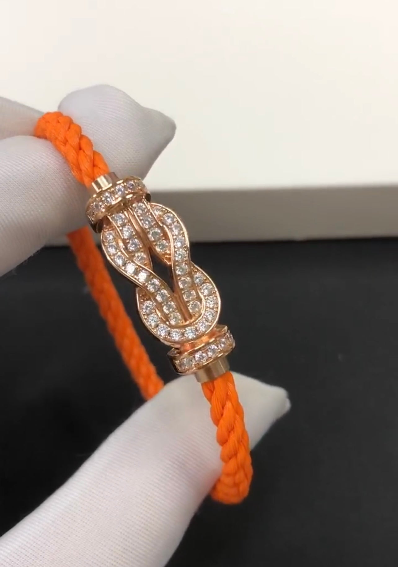 צמיד יוקרתי עם רצועת חבל כתומה ואבזם אינסוף בגוון זהב ורוד משובץ זירקונים נוצצים