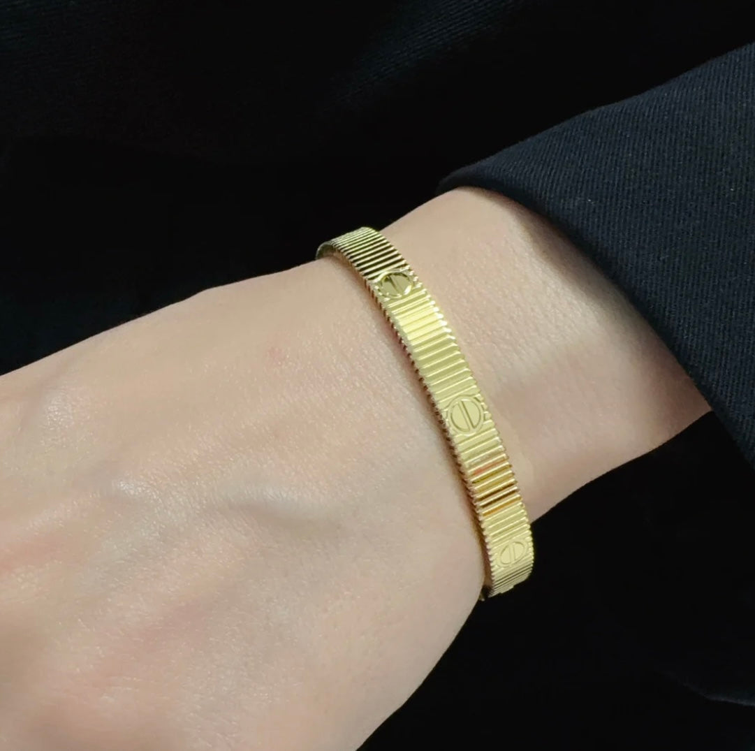 צמיד אלגנטי בגוון זהב מבריק עם פסים בעיצוב מודרני ונקי