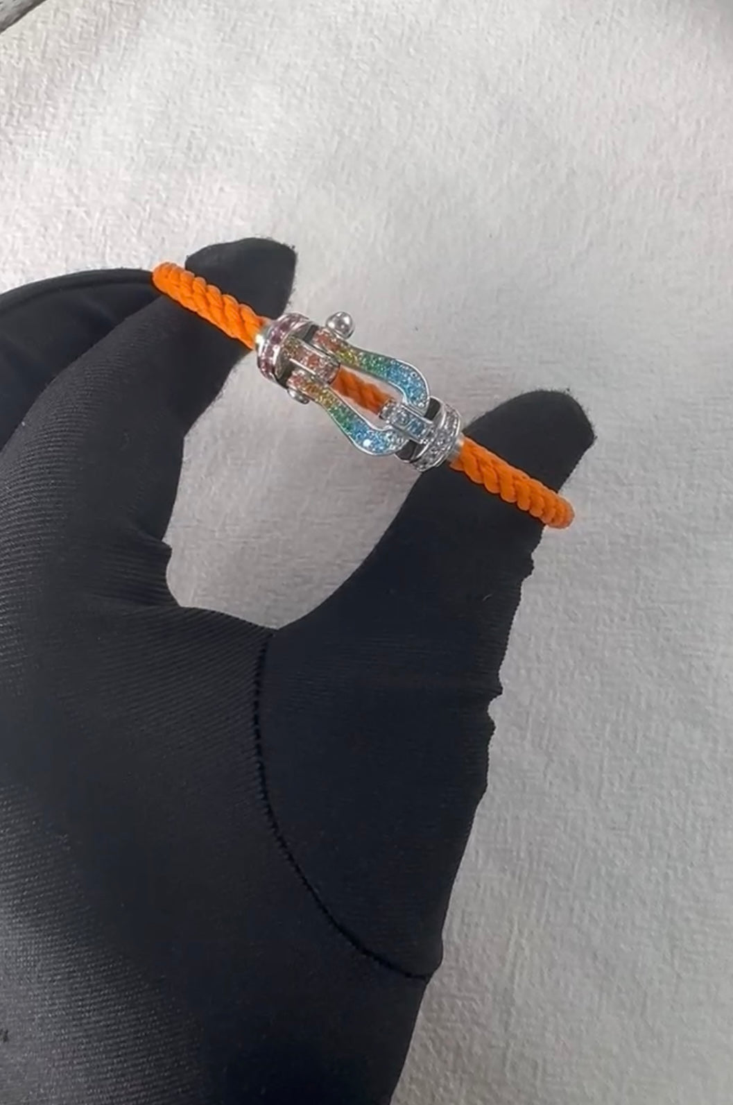 צמיד יוקרתי עם רצועת חבל כתומה ואבזם בגוון כסף משובץ בזירקונים צבעוניים