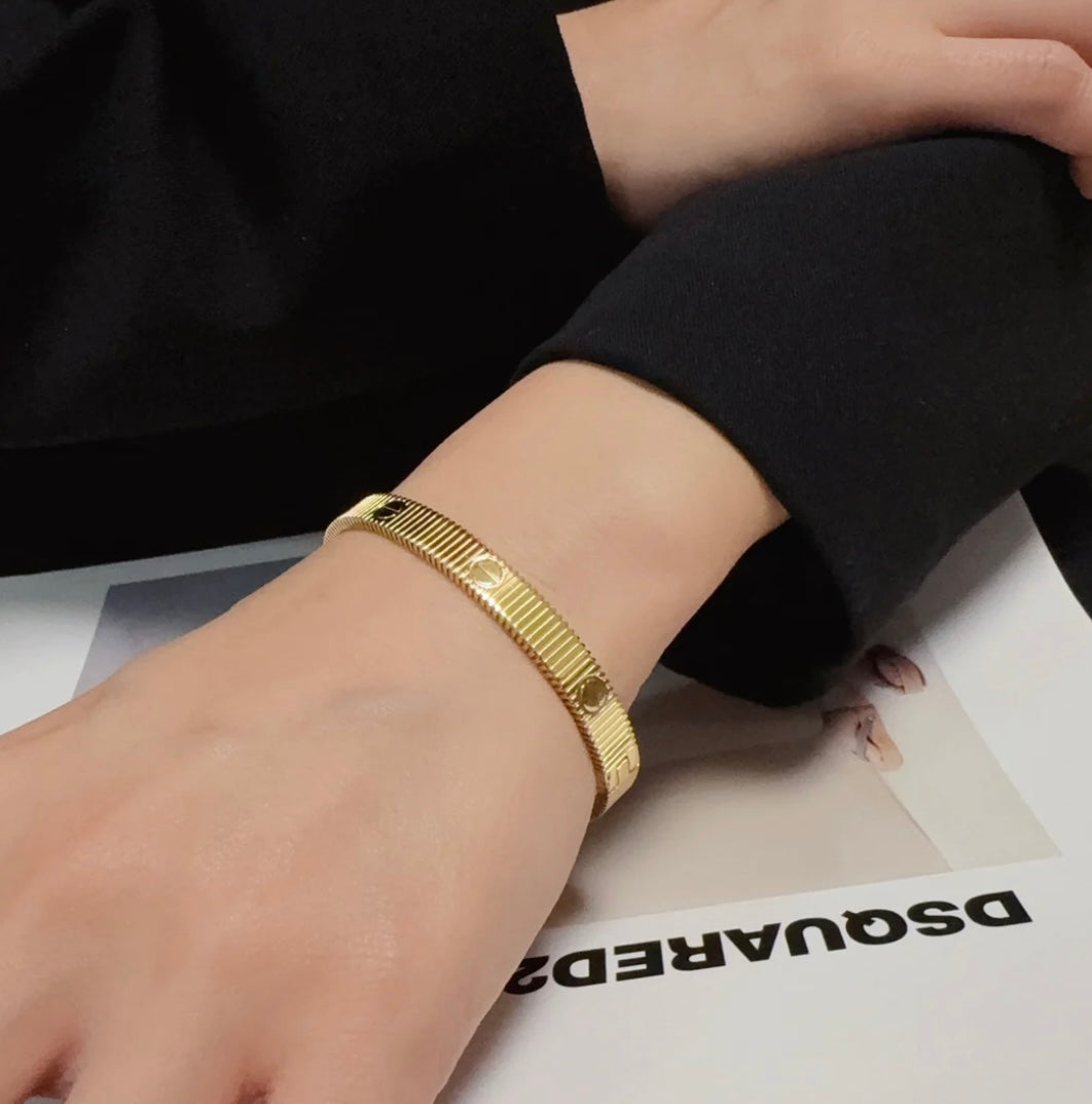 צמיד אלגנטי בגוון זהב מבריק עם פסים בעיצוב מודרני ונקי