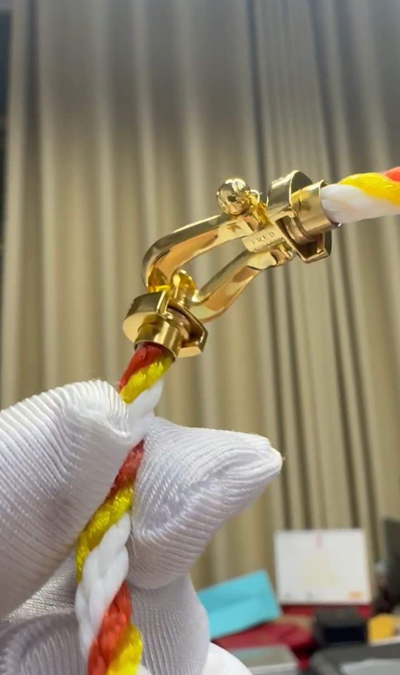 צמיד יוקרתי עם רצועת חבל בגווני כתום, לבן וצהוב ואבזם בגוון זהב משובץ בזירקונים כתומים