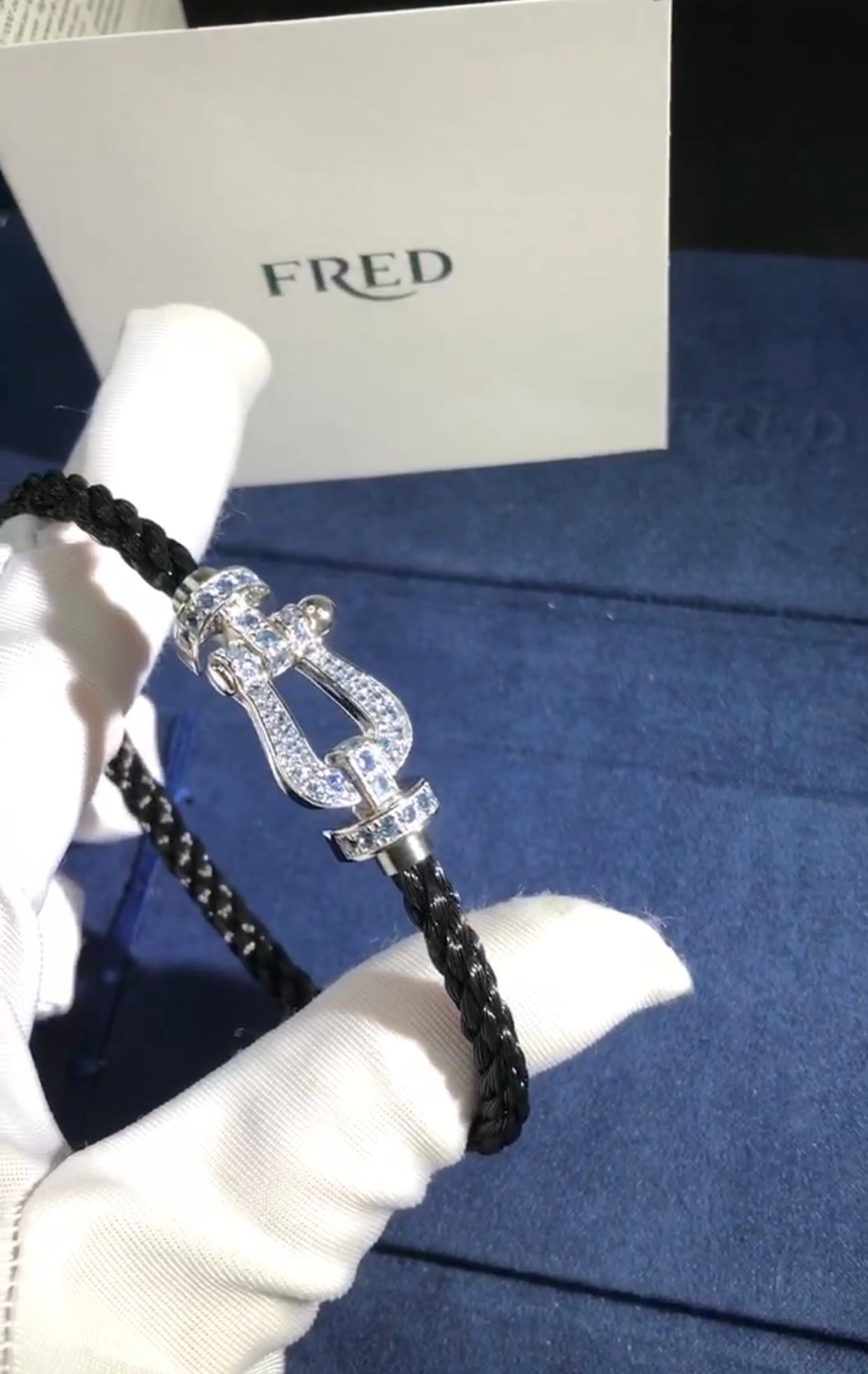 צמיד יוקרתי עם רצועת חבל שחורה ואבזם בגוון כסף משובץ זירקונים בגוון תכלת