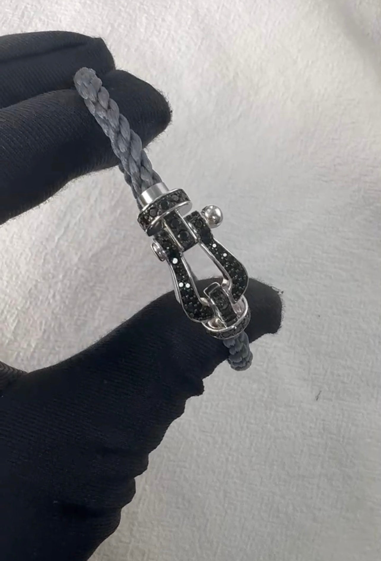 צמיד יוקרתי עם רצועת חבל אפורה ואבזם בגוון כסף משובץ בזירקונים שחורים