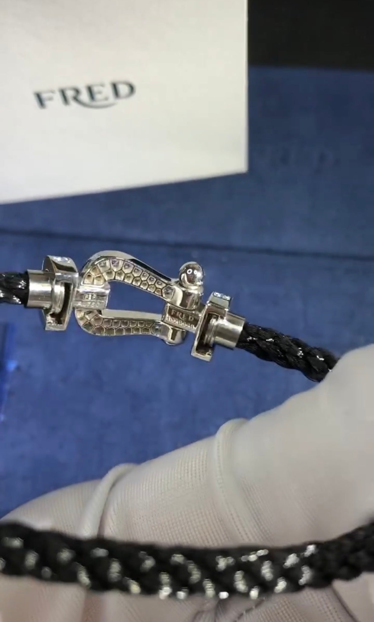 צמיד יוקרתי עם רצועת חבל שחורה ואבזם בגוון כסף משובץ זירקונים בגוון תכלת