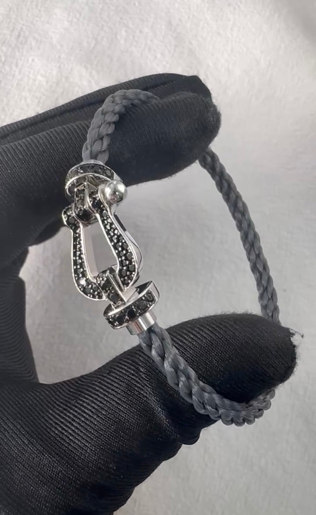 צמיד יוקרתי עם רצועת חבל אפורה ואבזם בגוון כסף משובץ בזירקונים שחורים