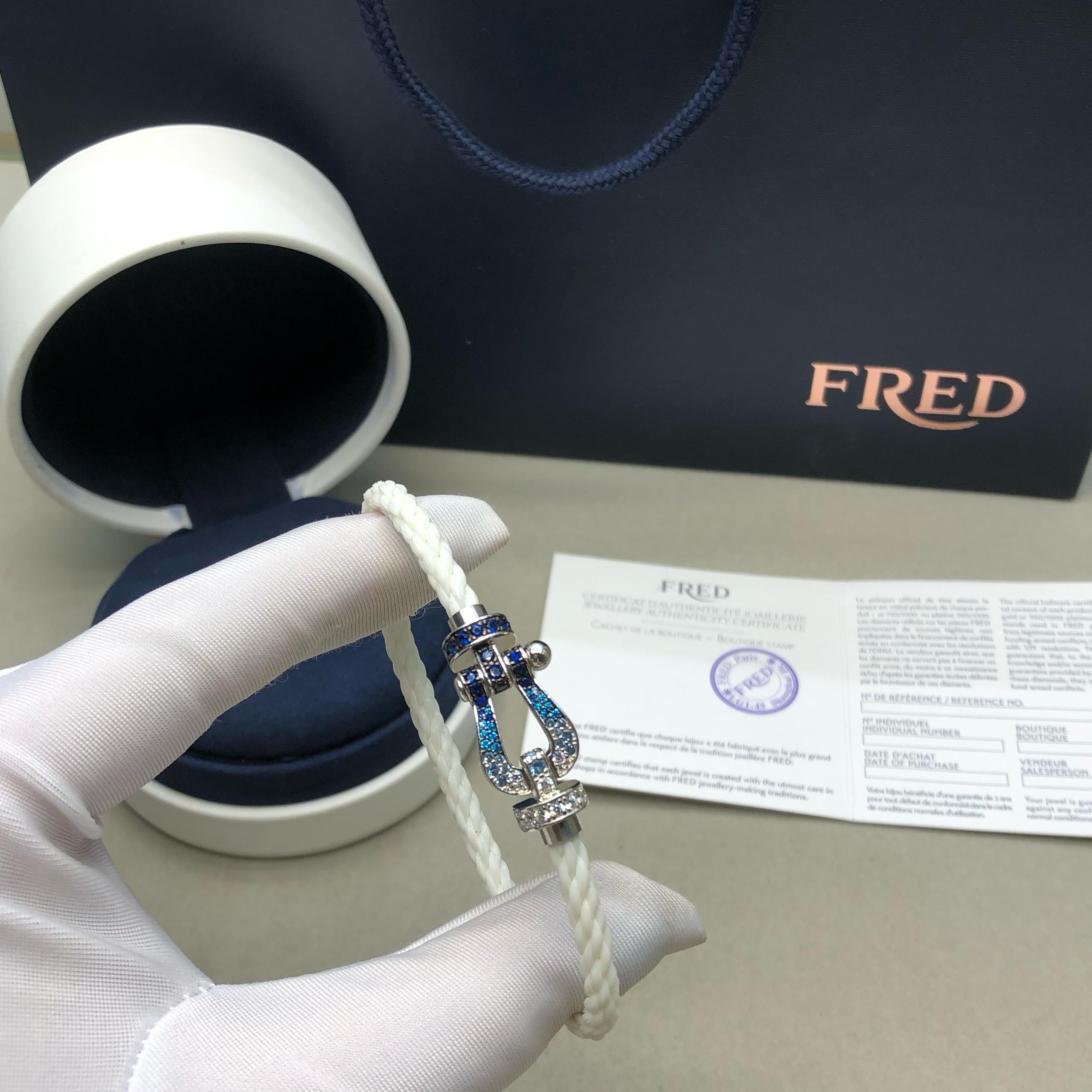 צמיד יוקרתי עם רצועת חבל לבנה ואבזם בגוון כסף משובץ בזירקונים כחולים ולבנים