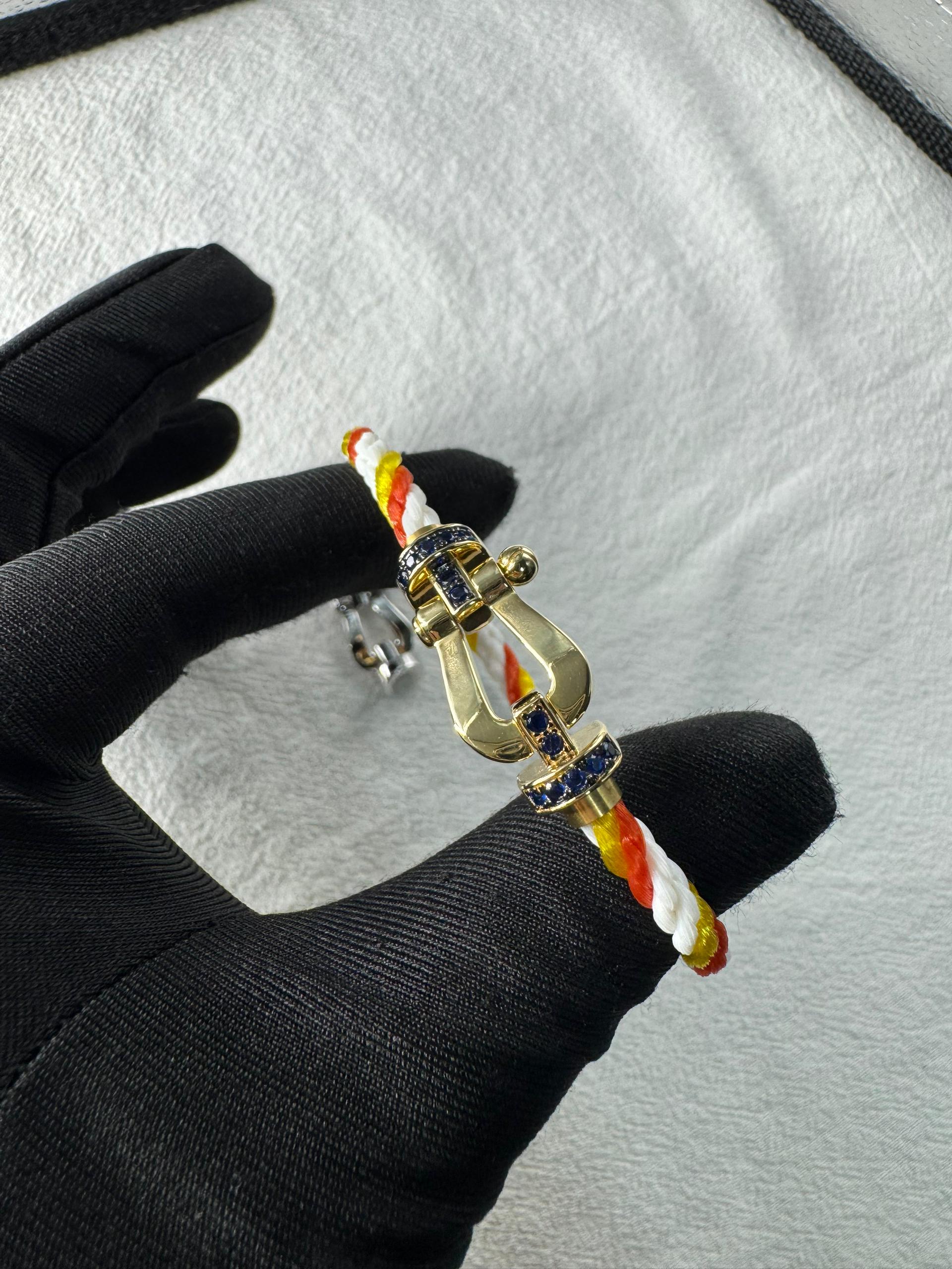 צמיד יוקרתי עם רצועת חבל צבעונית ואבזם בגוון זהב משובץ זירקונים כחולים