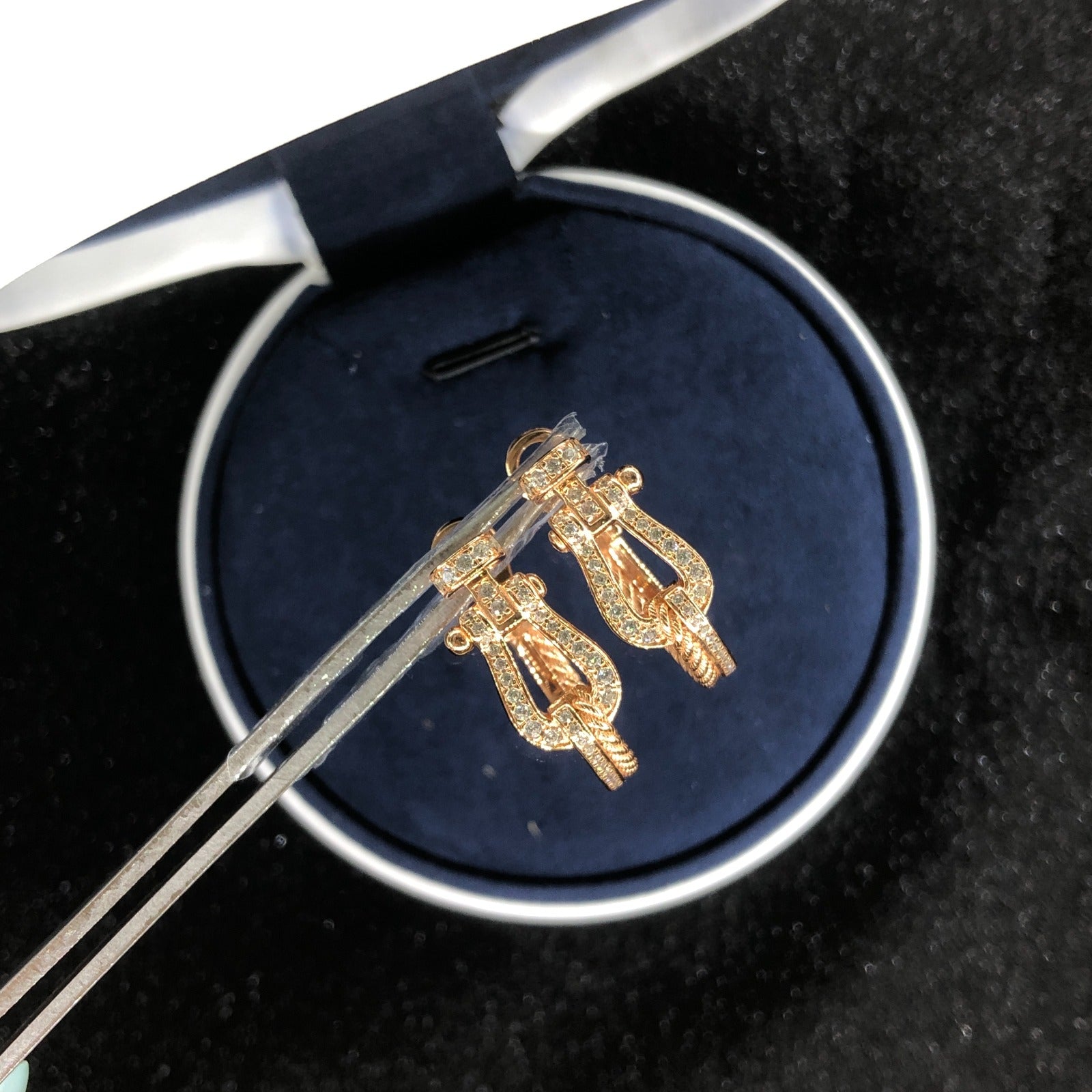 עגילי יוקרה בגוון זהב ורוד עם שיבוץ זירקונים ועיצוב חוט קלוע ייחודי