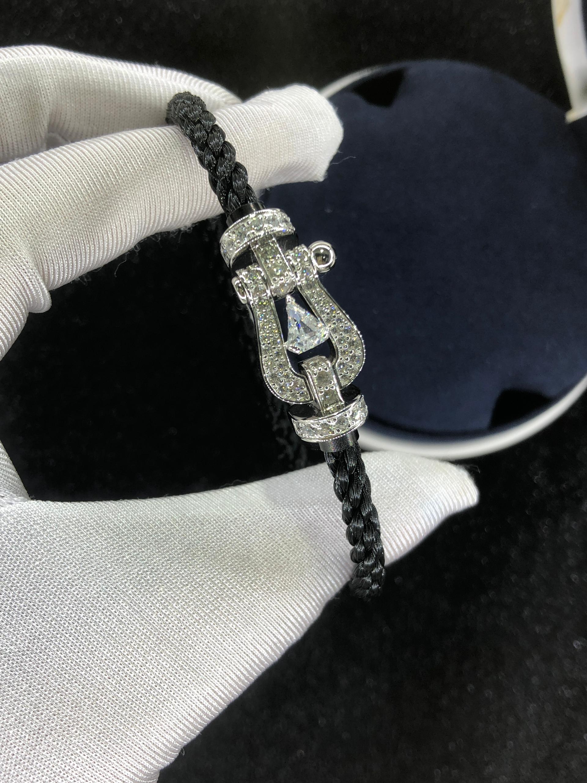 Bracelet luxueux avec une sangle en corde noire et une boucle argentée parsemée de zircons, avec une pierre centrale de 0,5 carat