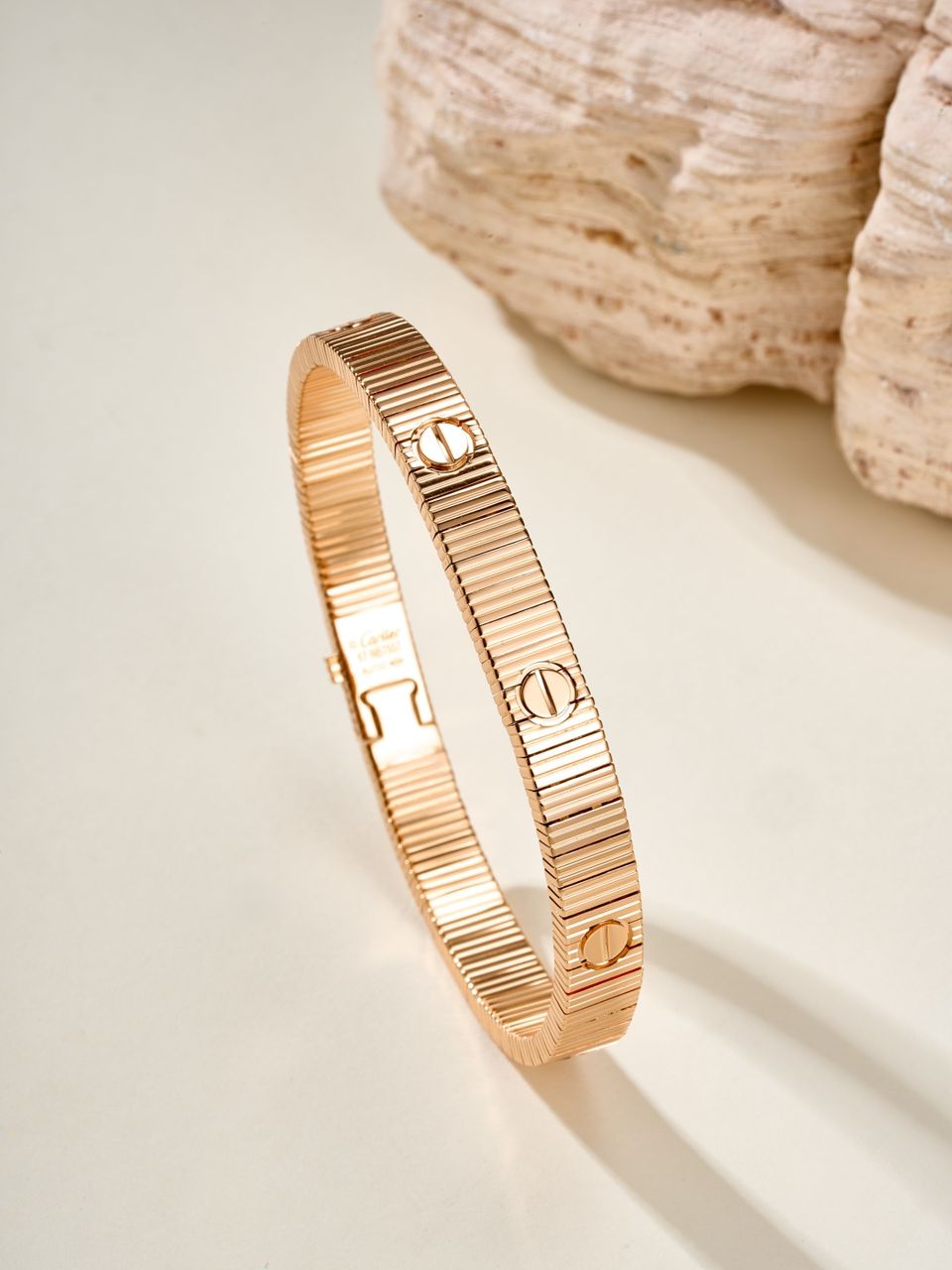 צמיד אלגנטי בגוון זהב ורוד מבריק עם פסים בעיצוב מודרני ונקי