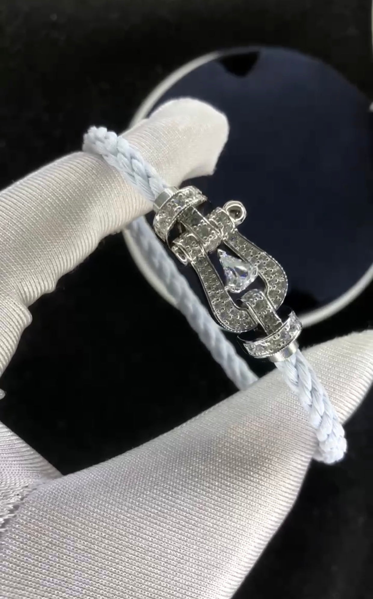 Bracelet luxueux avec une sangle en corde blanche et une boucle argentée parsemée de zircons, avec une pierre centrale de 0,5 carat