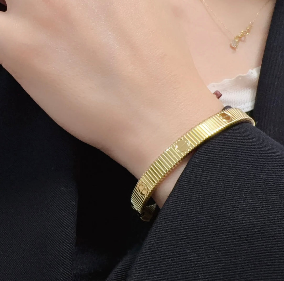 צמיד אלגנטי בגוון זהב מבריק עם פסים בעיצוב מודרני ונקי