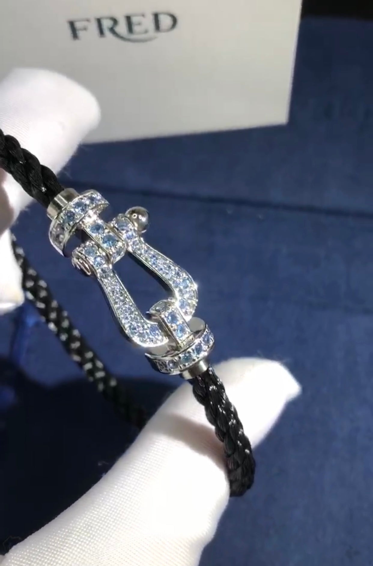 צמיד יוקרתי עם רצועת חבל שחורה ואבזם בגוון כסף משובץ זירקונים בגוון תכלת