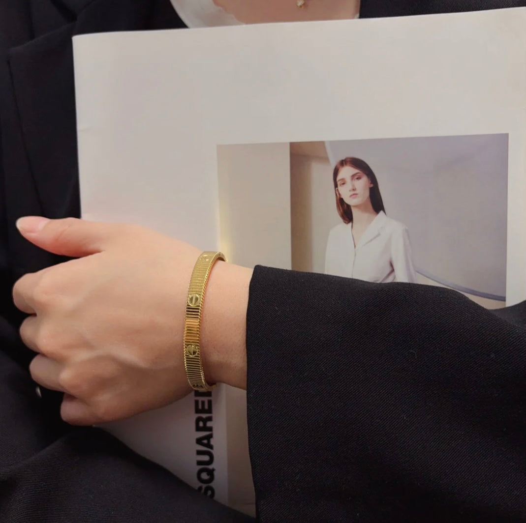 צמיד אלגנטי בגוון זהב מבריק עם פסים בעיצוב מודרני ונקי