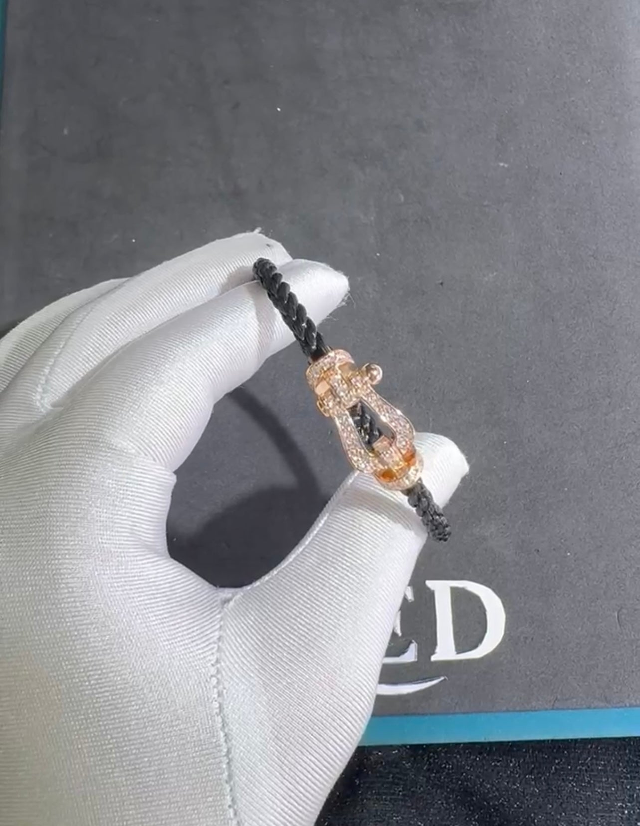 צמיד יוקרתי עם רצועת חבל שחורה ואבזם בגוון זהב ורוד משובץ בזירקונים